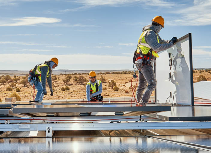 three construction workers installing solar panels